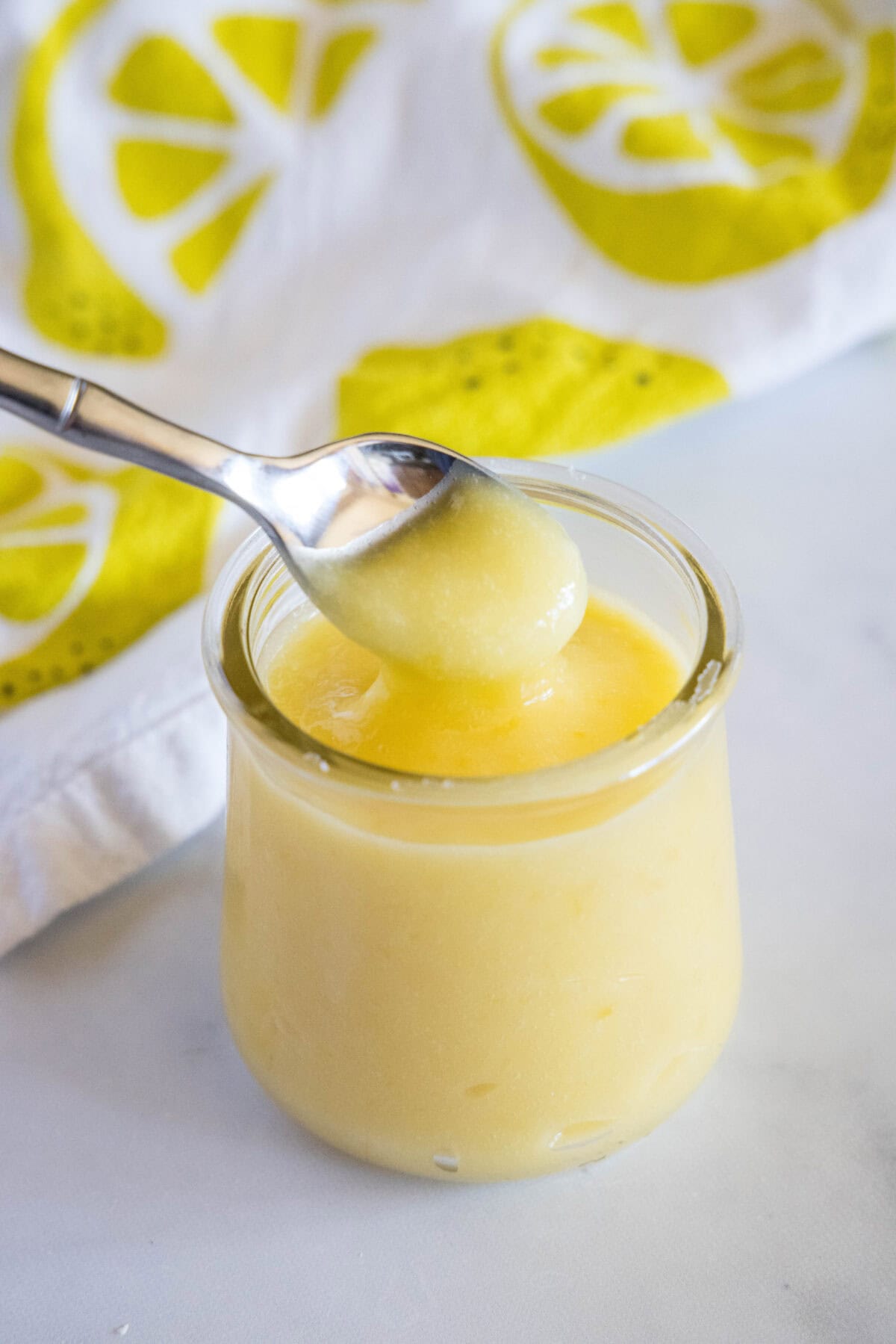 lemon curd being spooned out of a jar