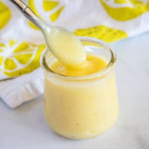 close up lemon curd in a jar with a spoon