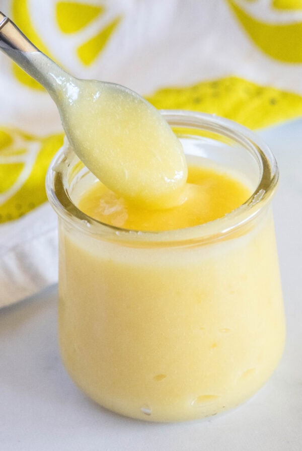 close up lemon curd in a jar with a spoon