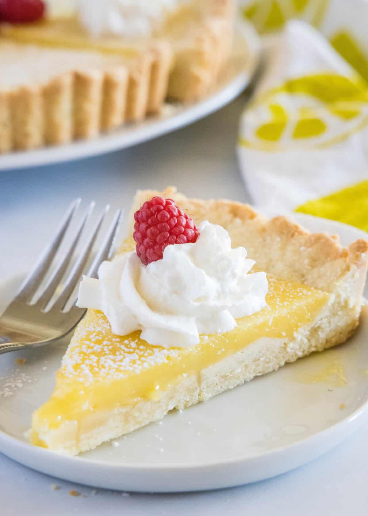 lemon tart slice on a plate with whipped cream