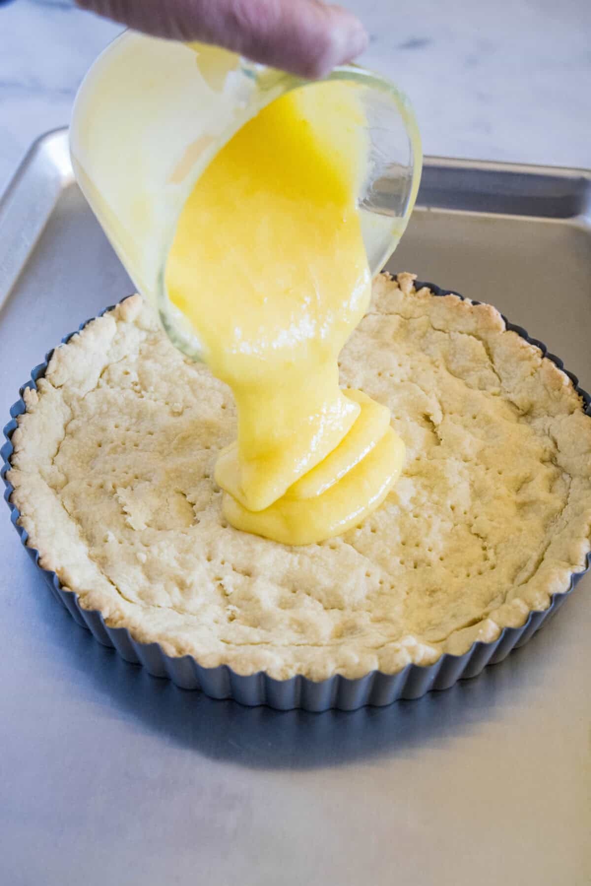 pouring lemon curd into baked tart shell