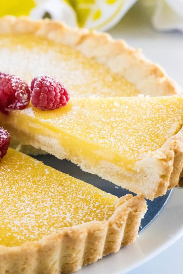 close up taking slice of lemon tart from the pan