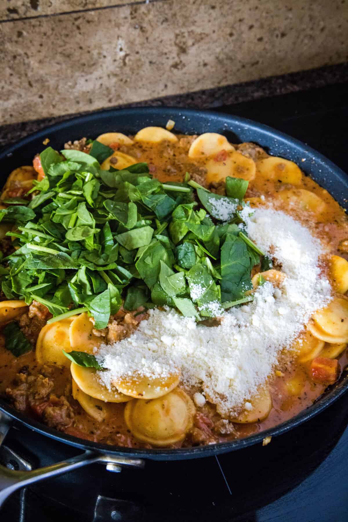 adding spinach and parmesan cheese to skillet
