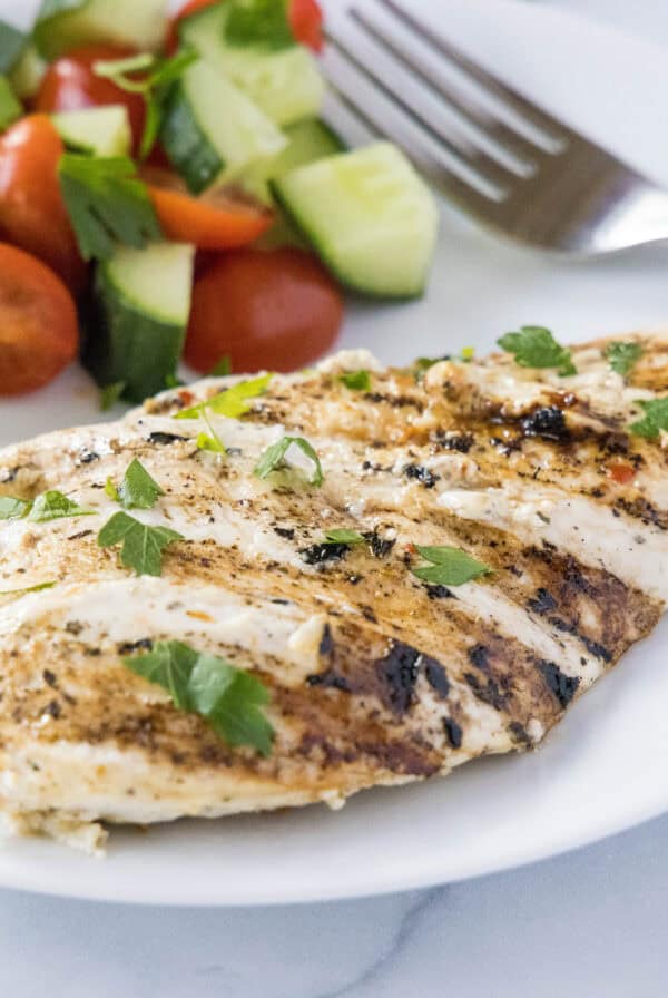 close up yogurt marinated chicken breast on a white plate