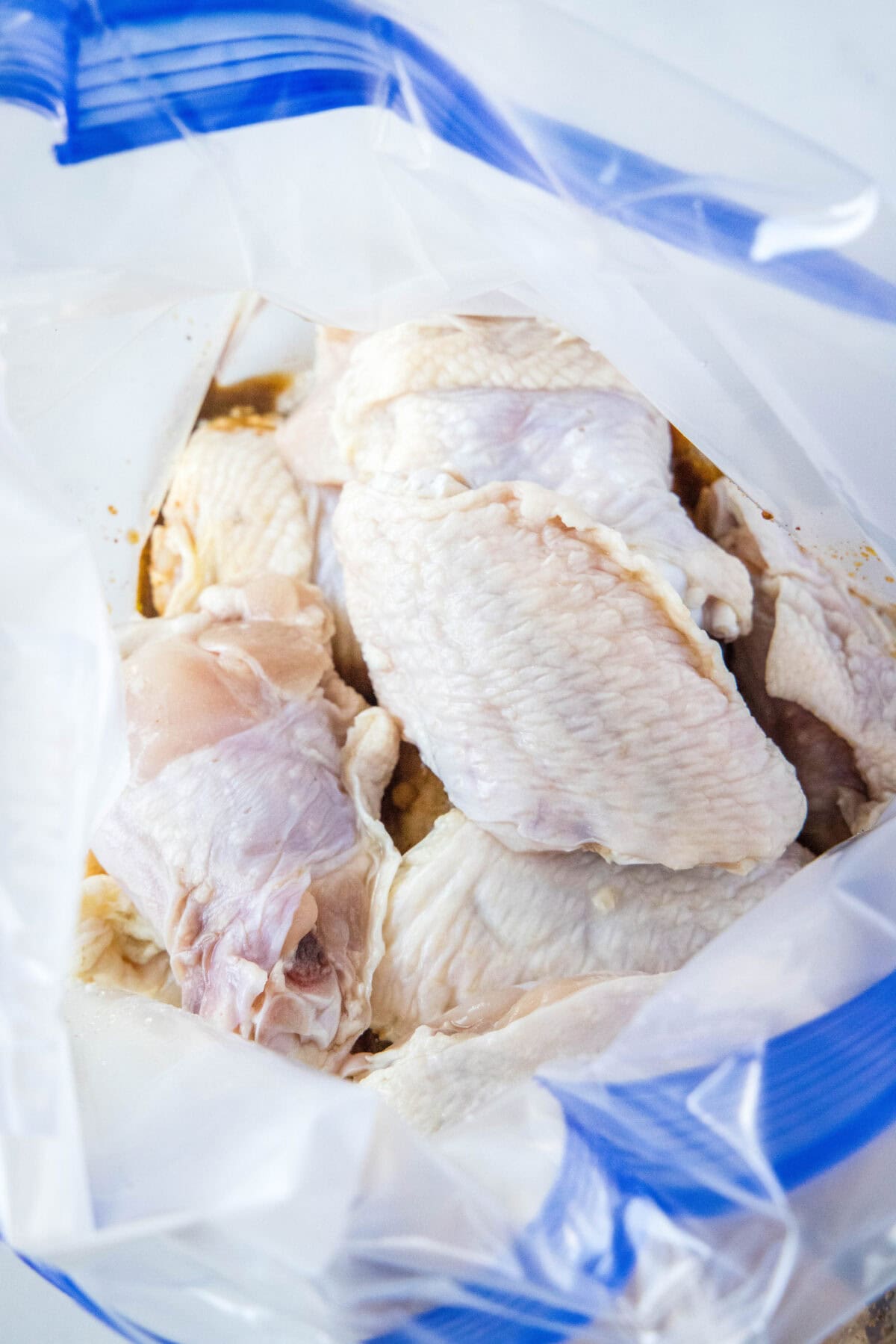 adding chicken wings to marinade