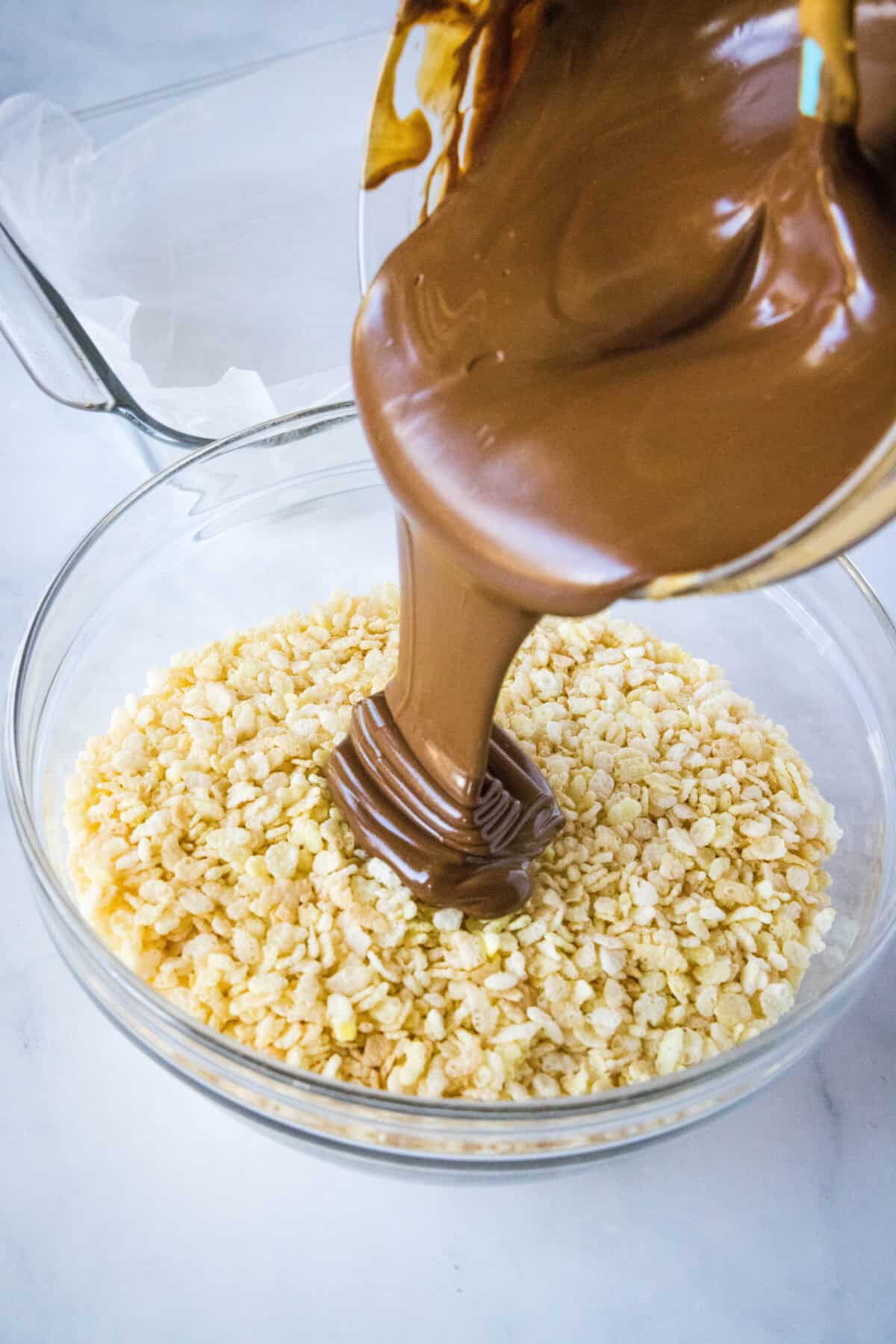 pouring melted chocolate over a bowl of rice krispies