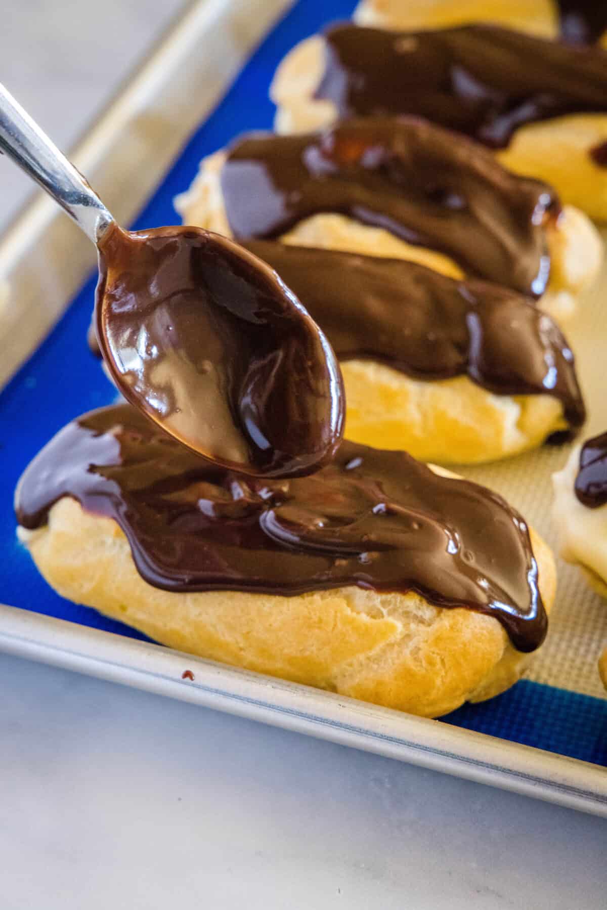 spooning chocolate over the eclairs