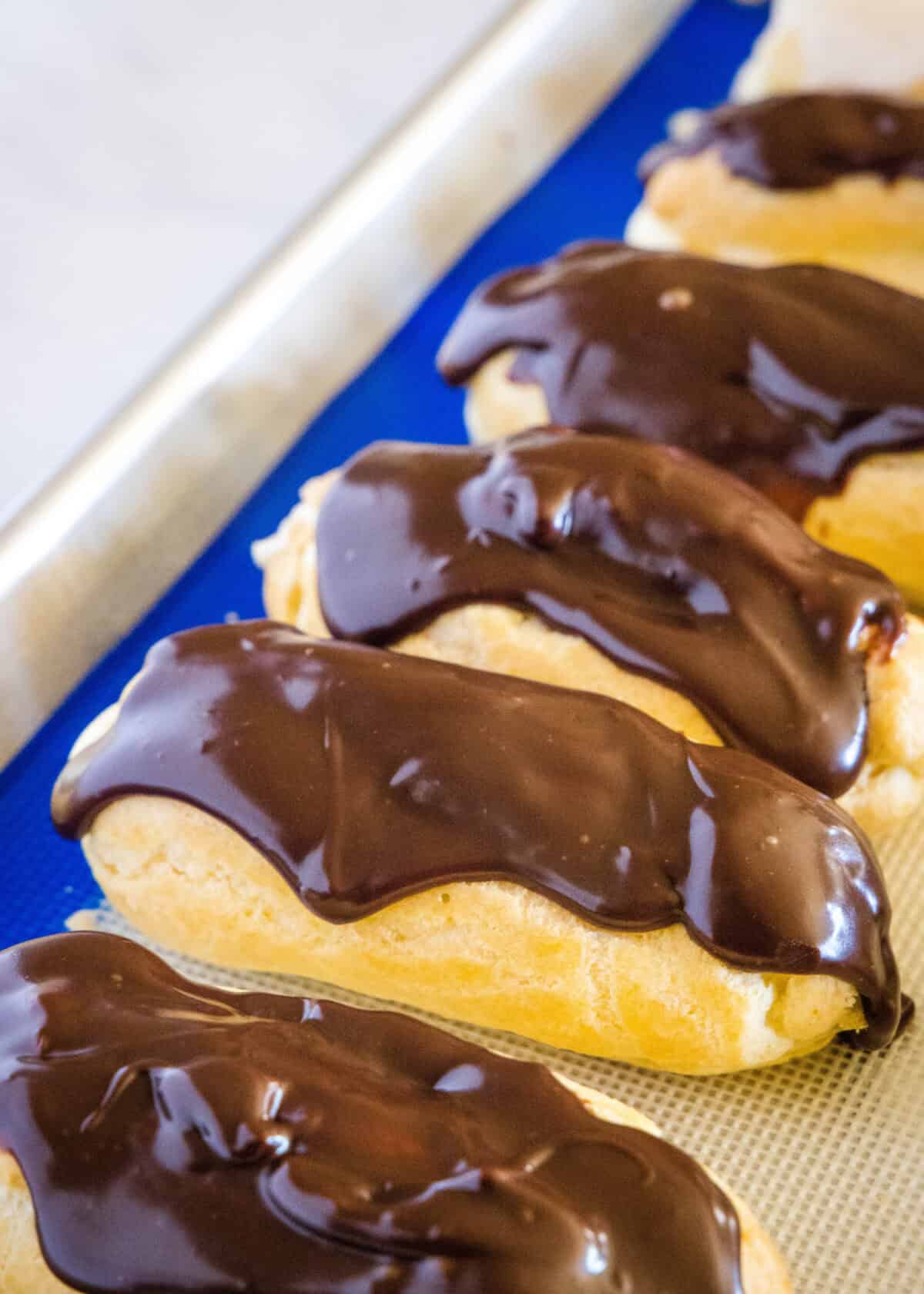 chocolate eclairs on a baking tray