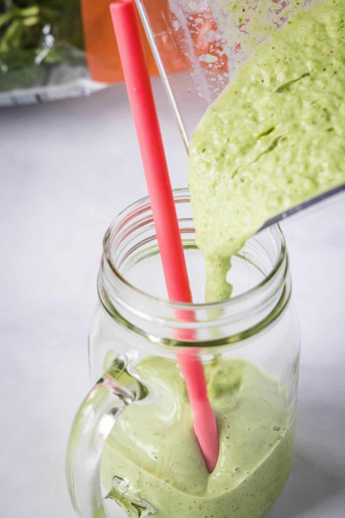 pouring kiwi spinach smoothie into a glass
