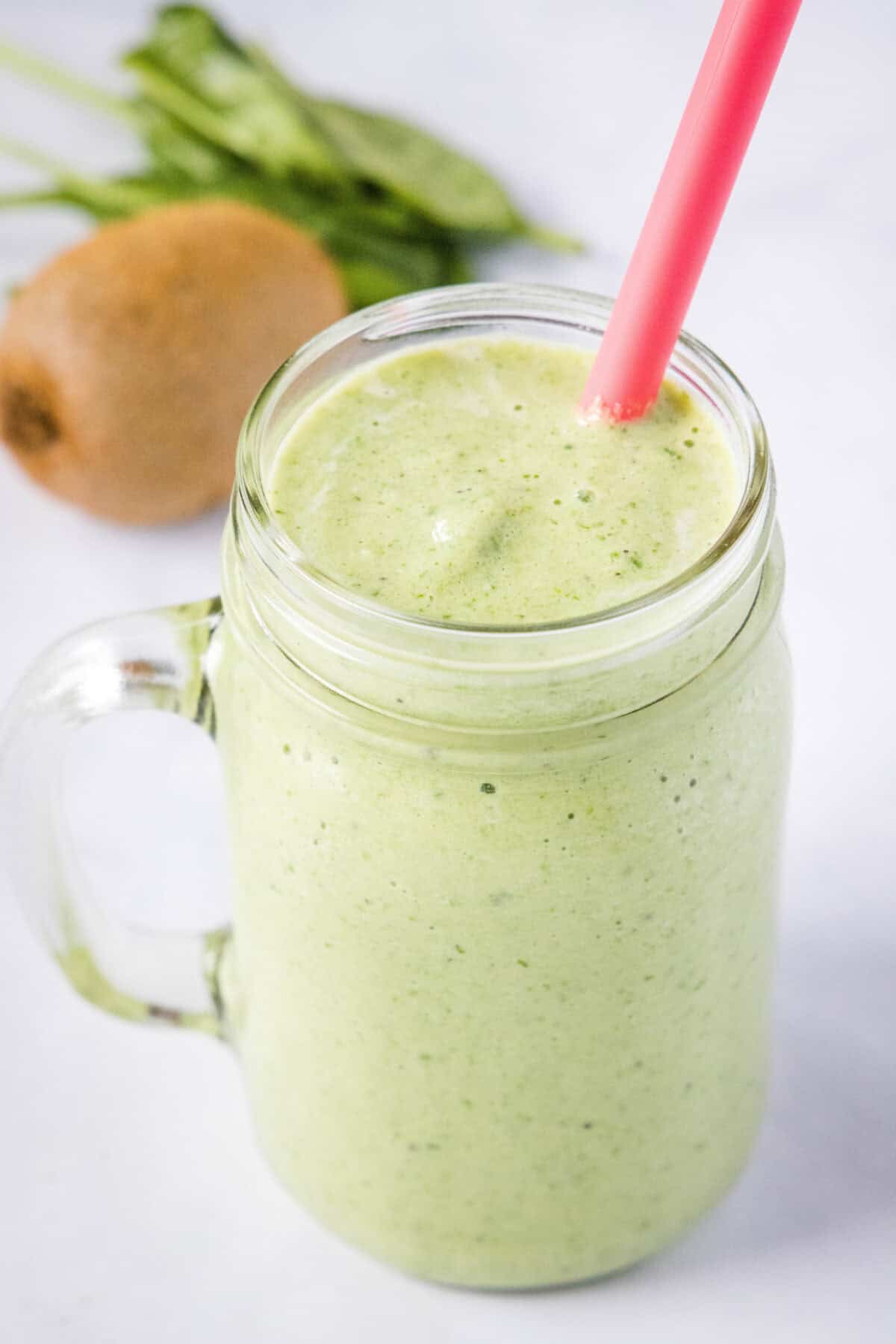 kiwi smoothie in a glass with straw