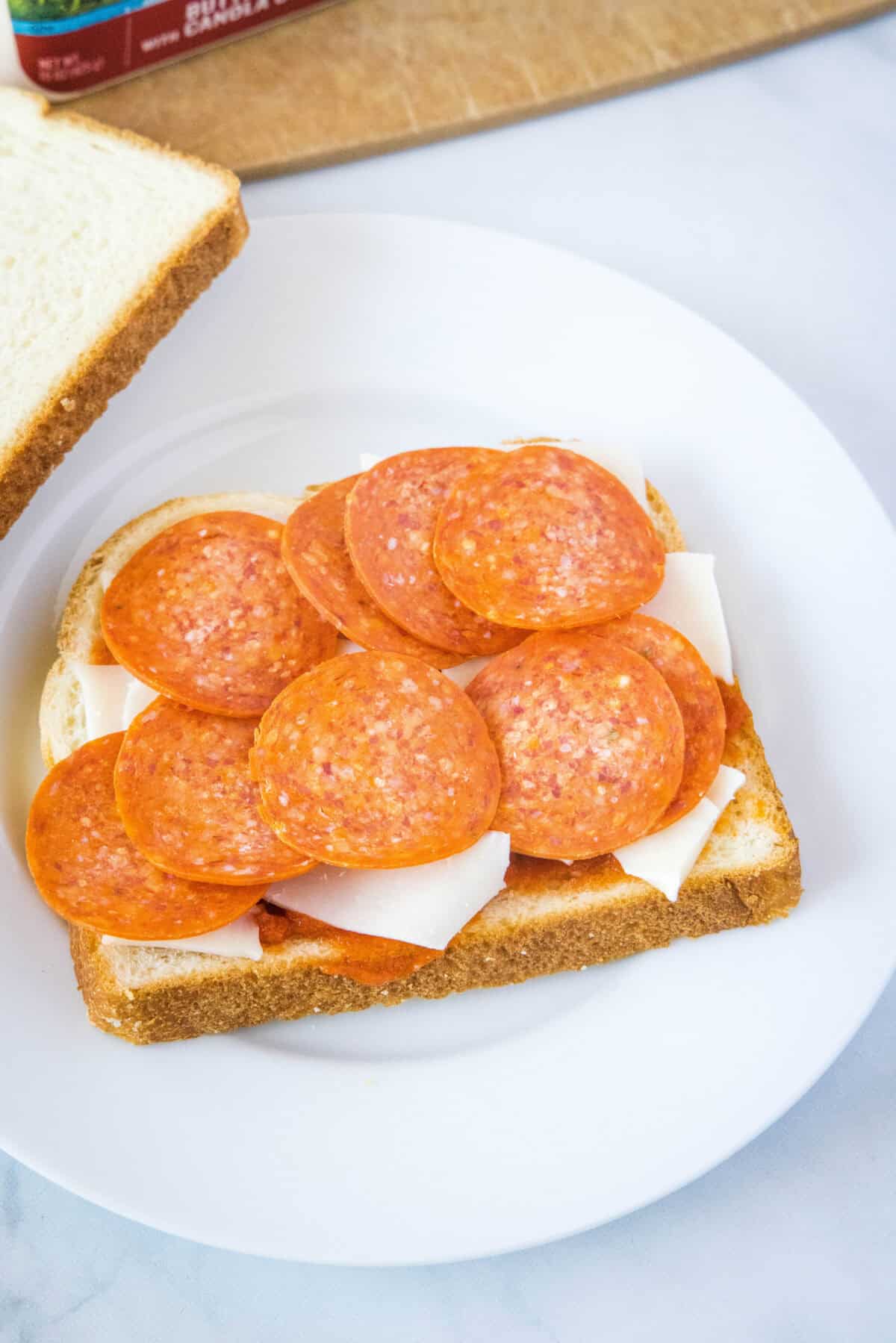 assembling grilled cheese with layer of pizza sauce, cheese, pepperoni