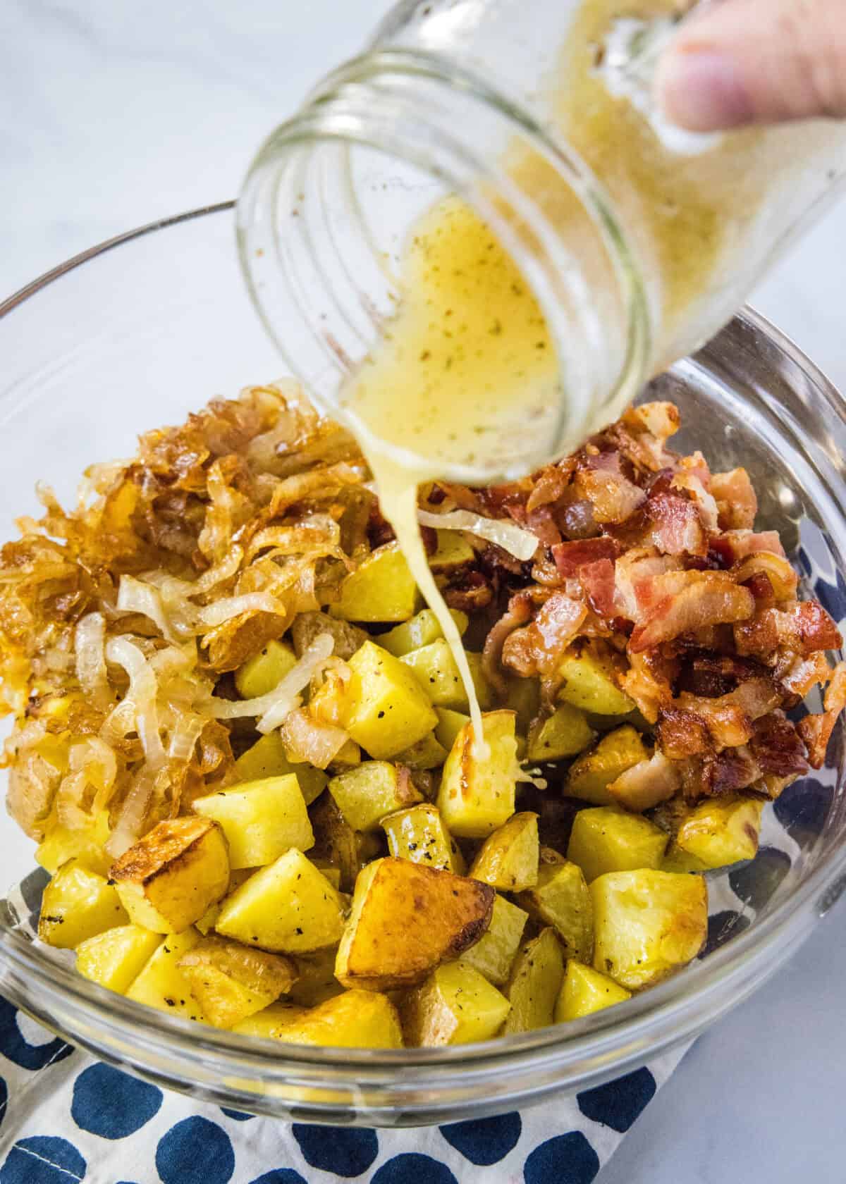 pouring dressing over potatoes, bacon and onions