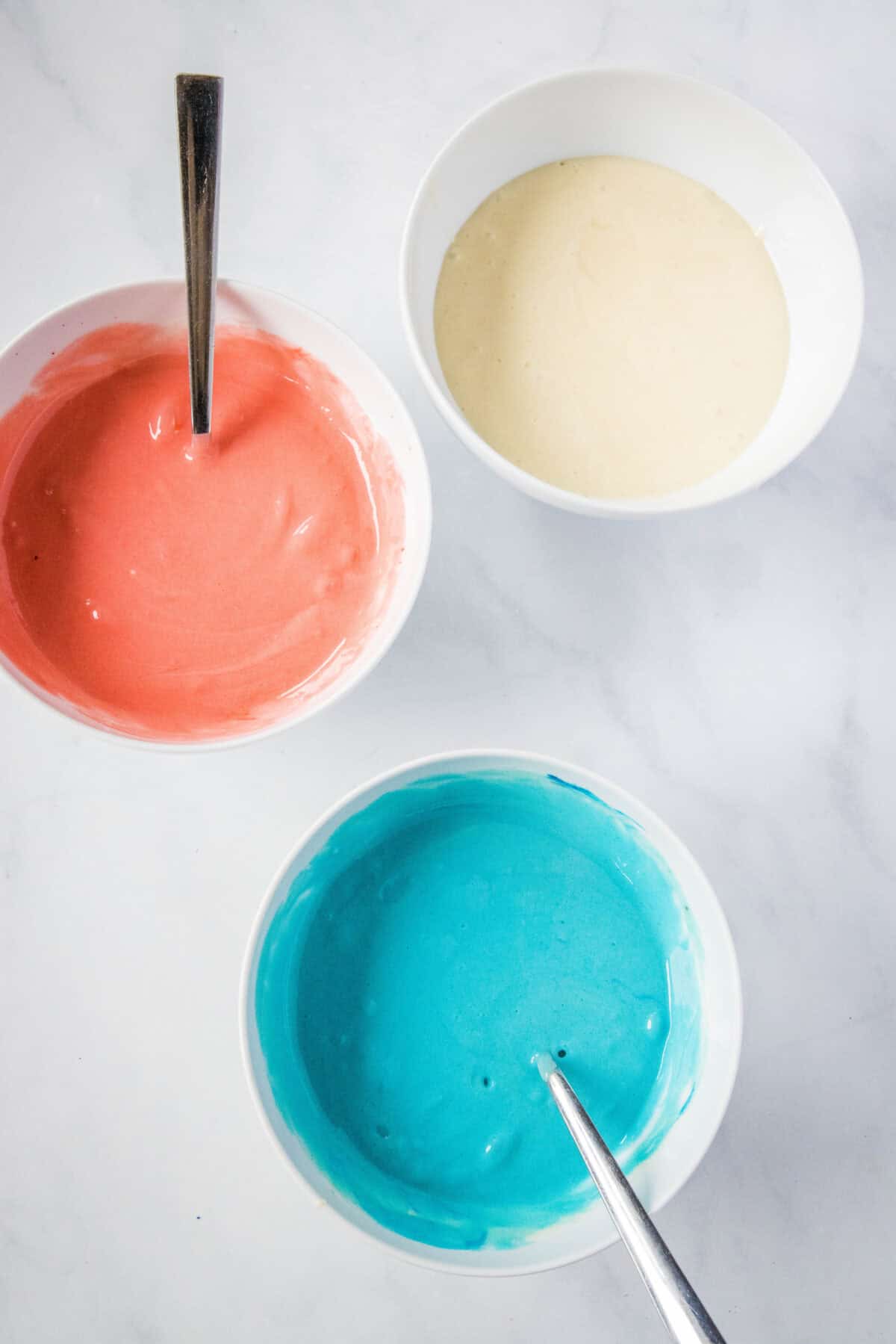 red white and blue cake batter in bowls