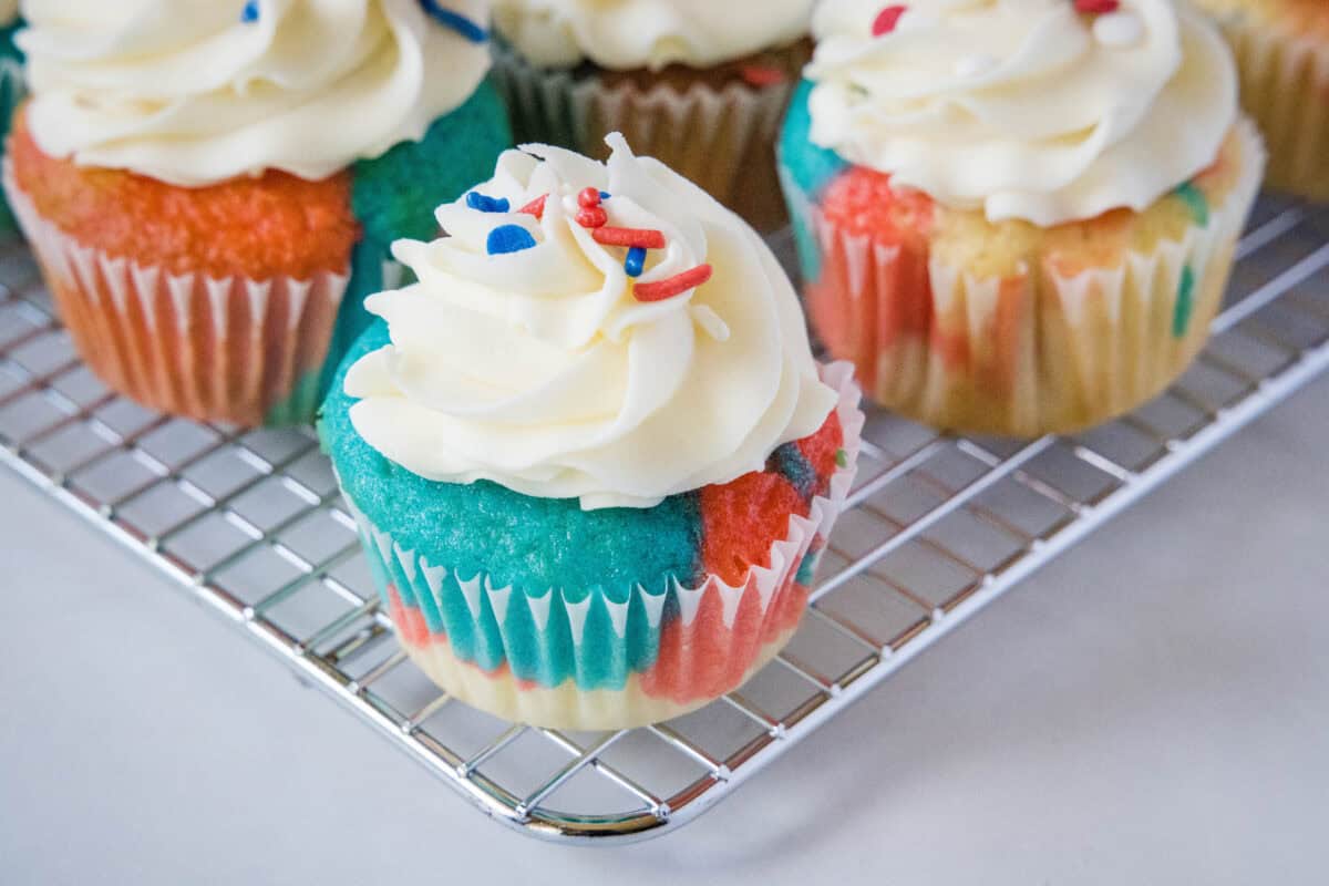 These festive 4th of July cupcakes feature red and blue swirled batter, fluffy homemade vanilla frosting, and patriotic sprinkles. They are the perfect easy dessert for your Independence Day celebration!