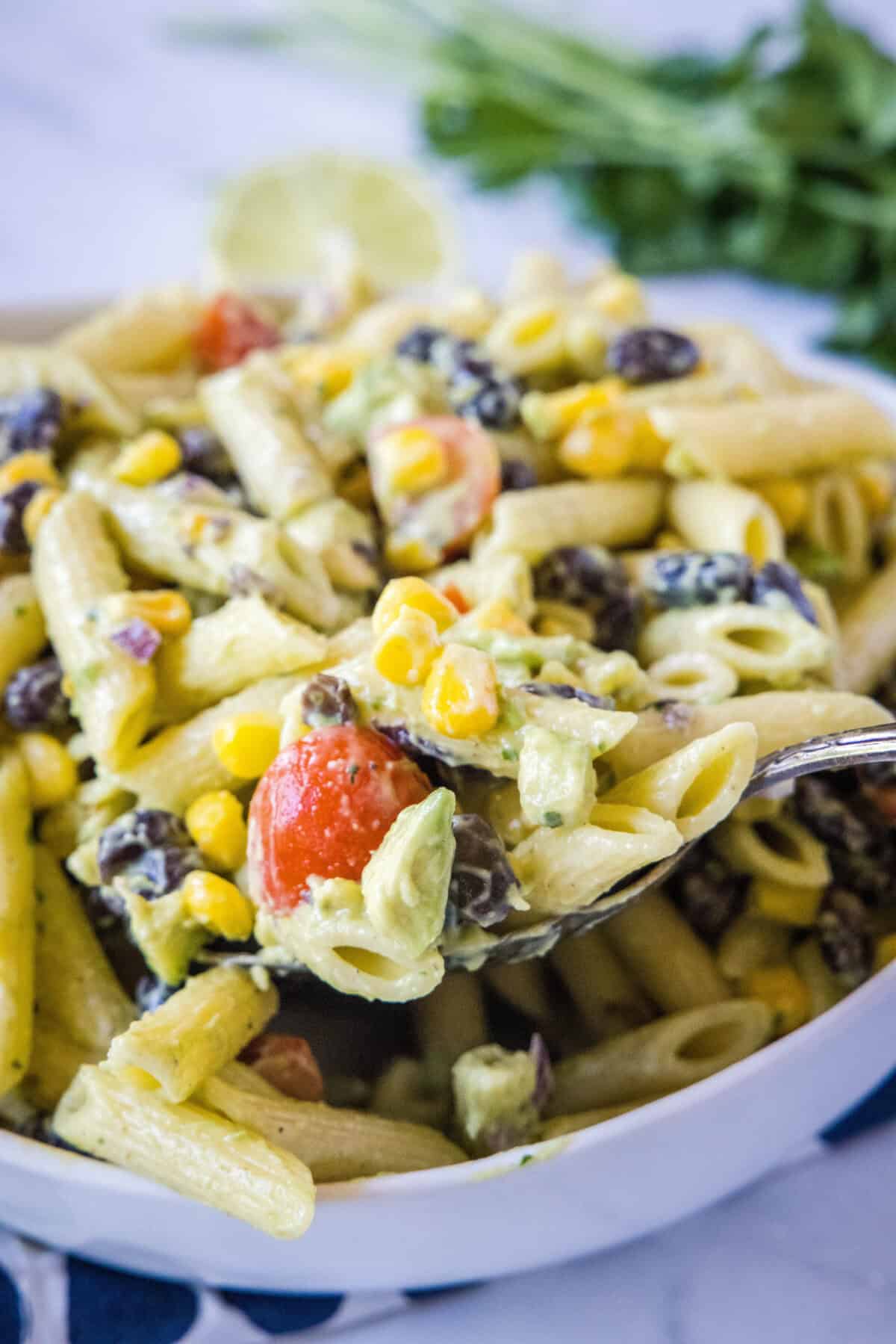 spooning pasta salad over a bowl
