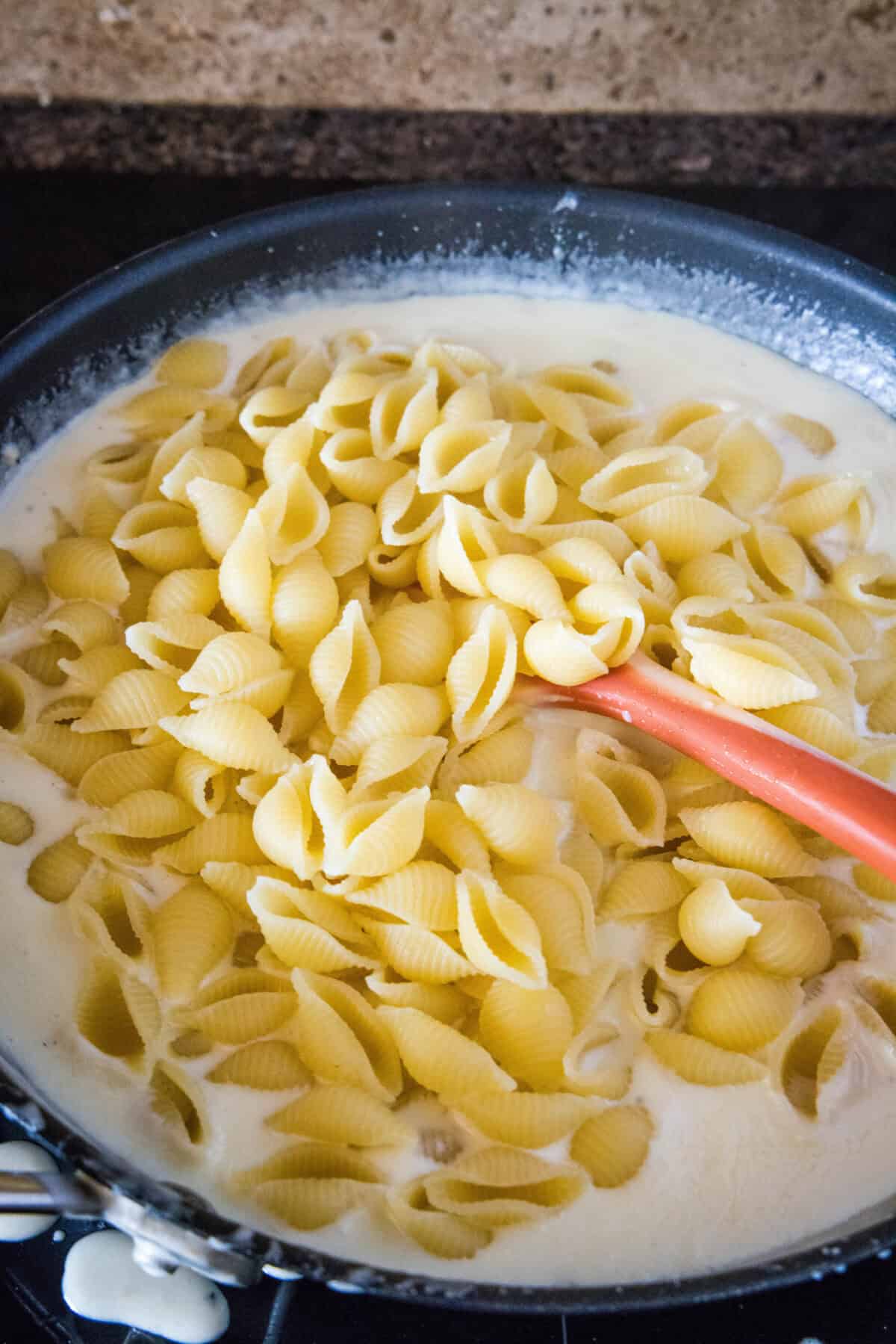 adding cooked pasta to cheese sauce