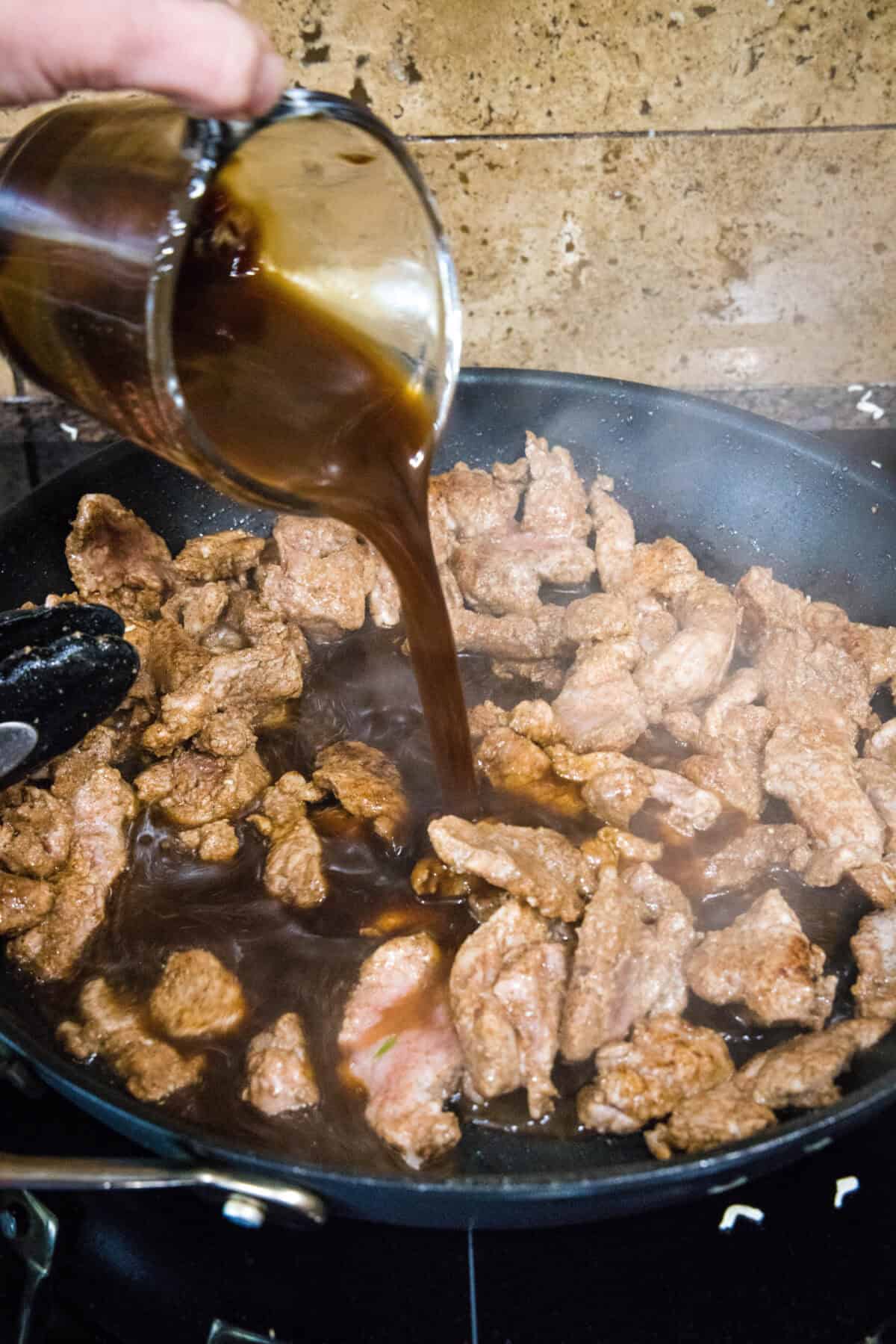 pouring sauce into skillet with pork