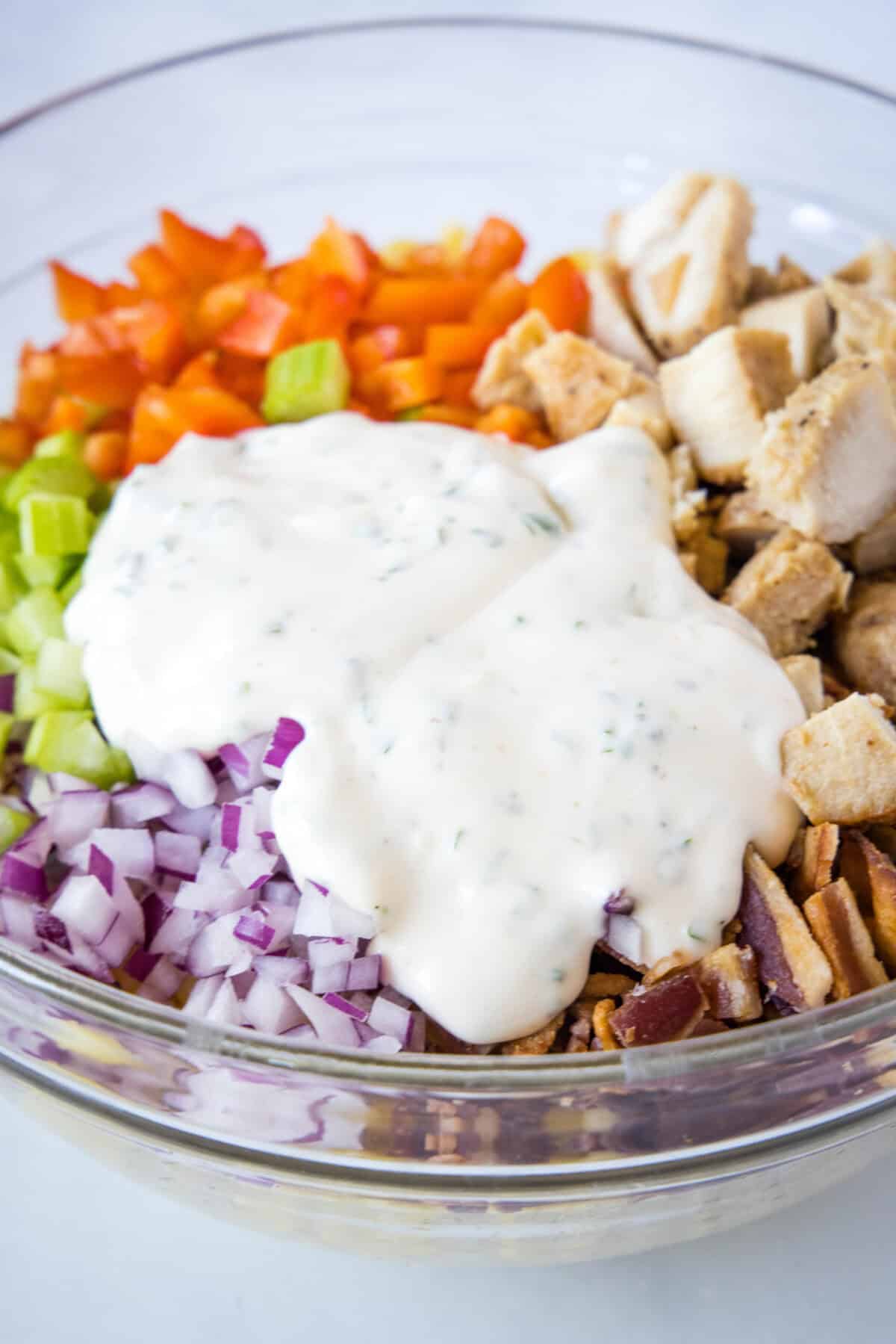 pouring dressing over chicken macaroni salad