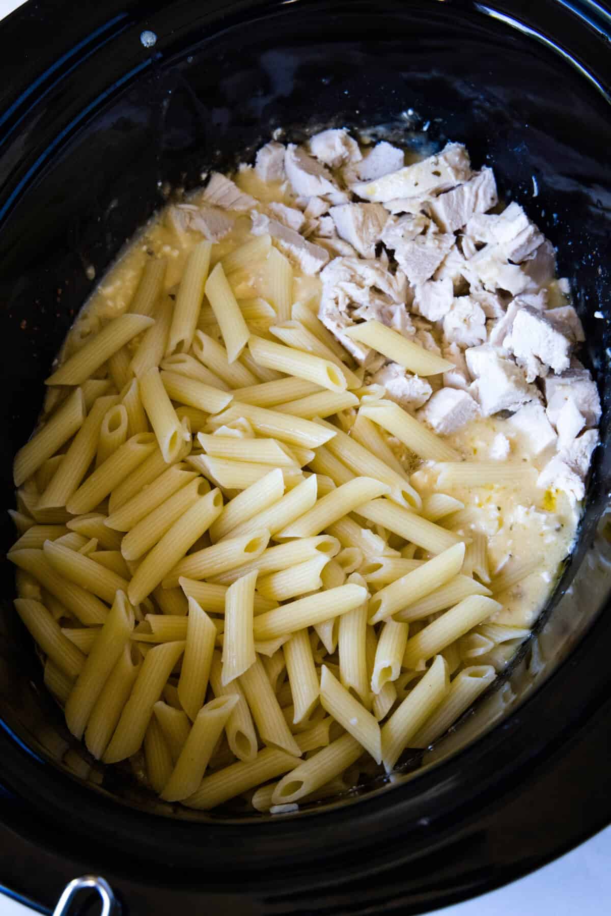 adding pasta to crockpot with chicken