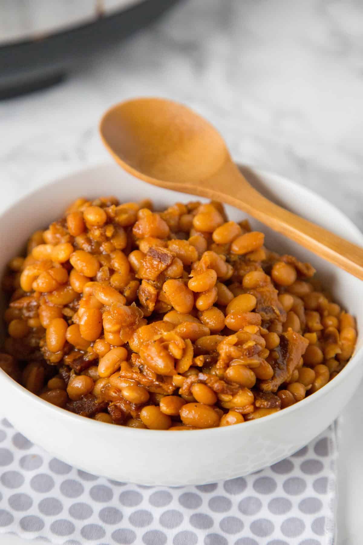serving bowl with baked beans and a wooden spoon