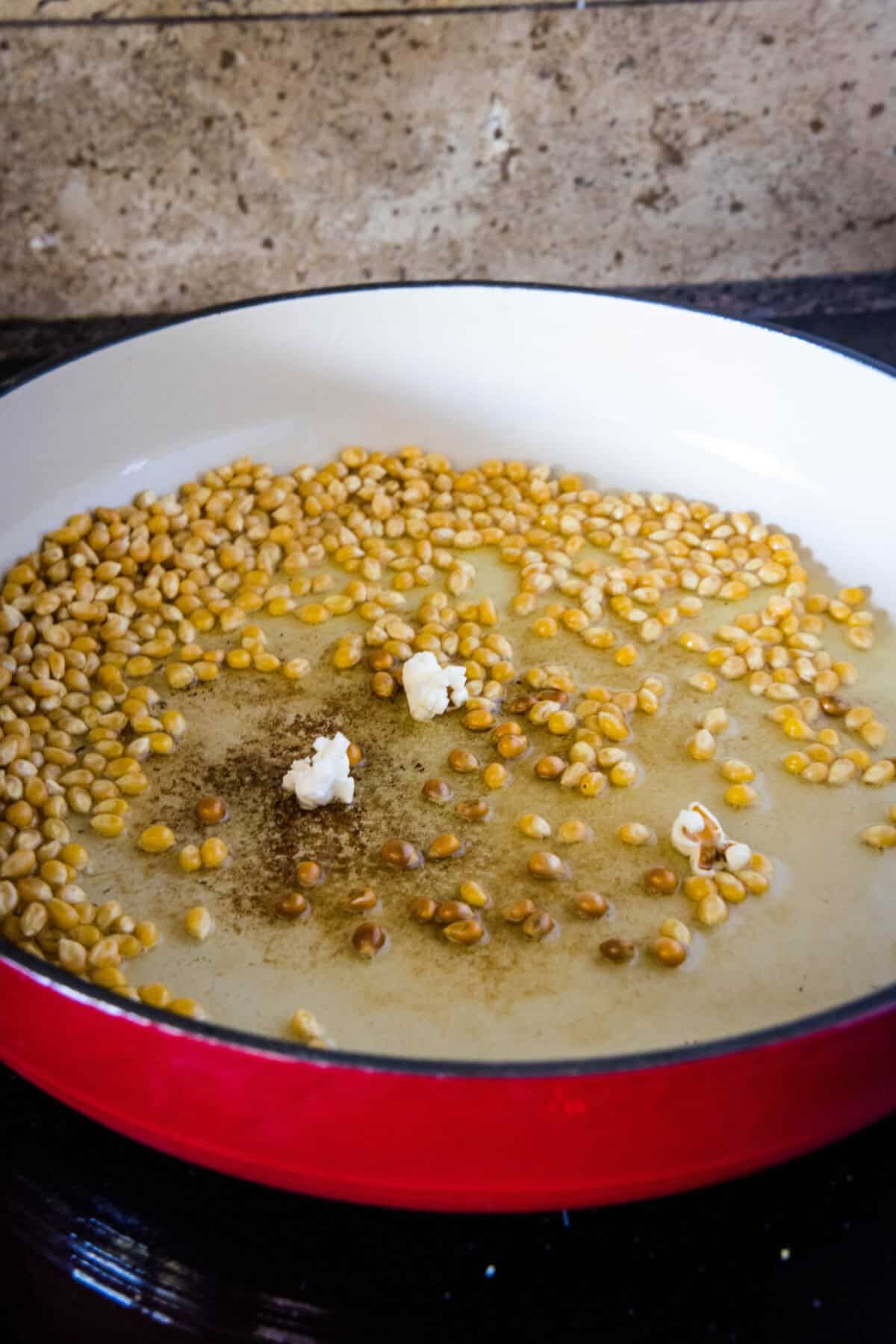 adding popcorn kernels to melted butter