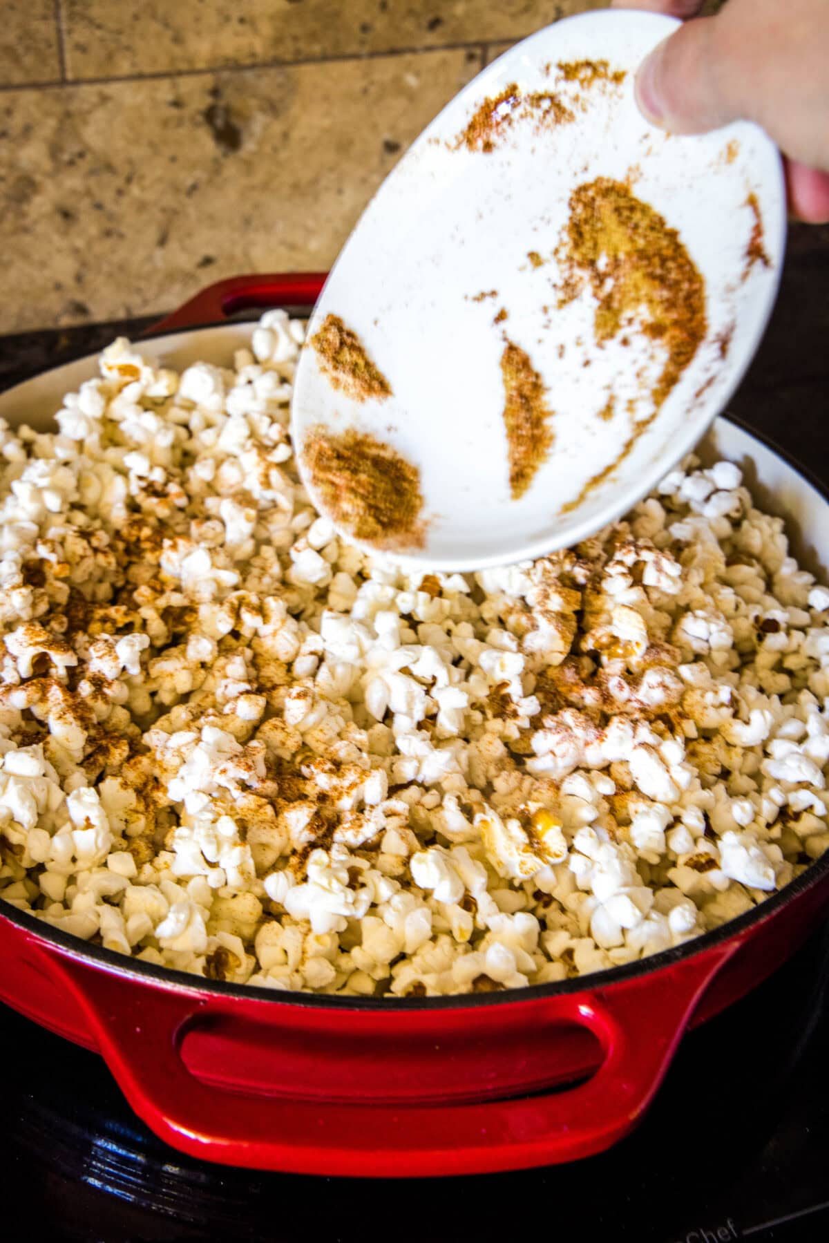 adding spices to popped popcorn
