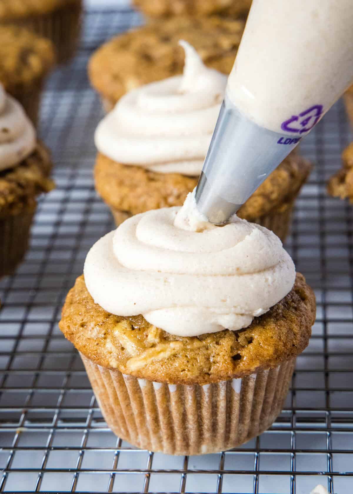 piping frosting on apple cupcake