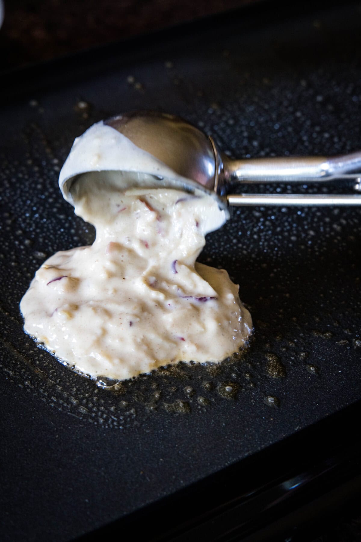 scooping apple pancakes onto griddle