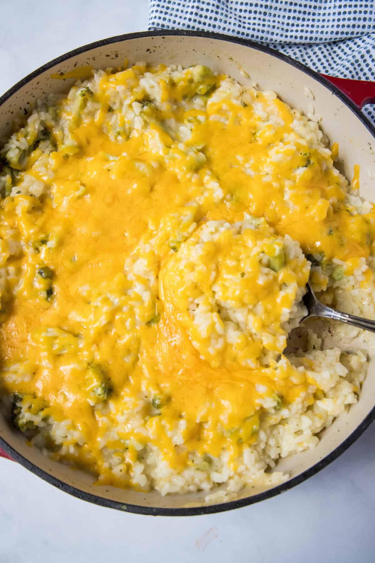 looking down on a cheese rice in skillet with a serving spoon