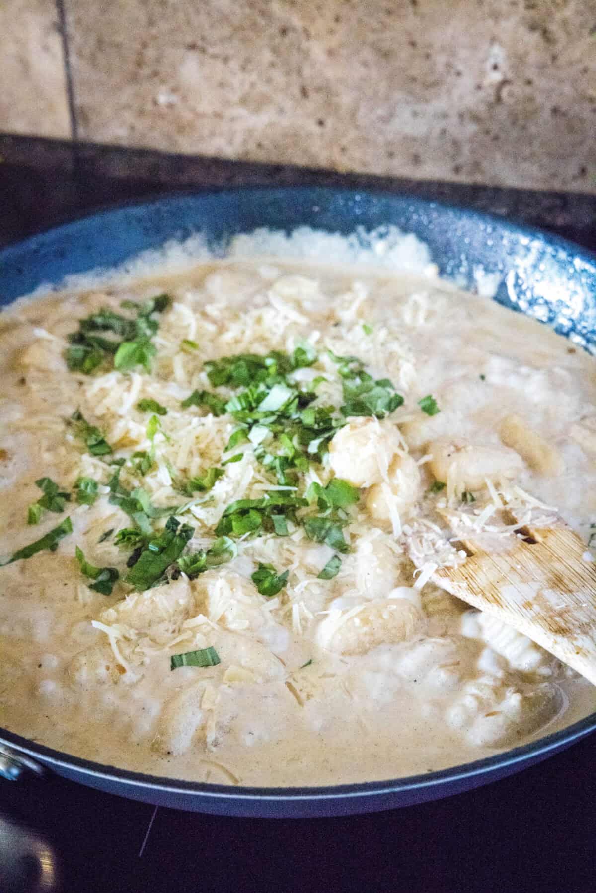 adding parmesan cheese and basil to cream sauce
