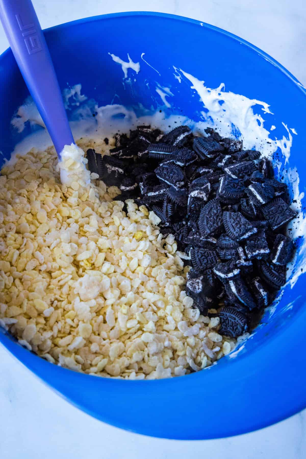 adding rice krispies and oreos to melted marshmallows