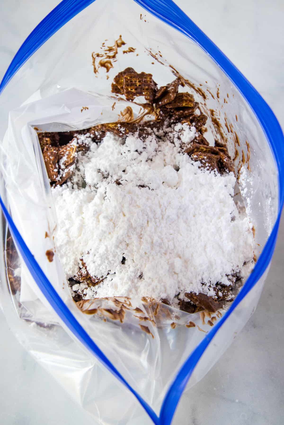 adding powdered sugar to puppy chow in a plastic bag