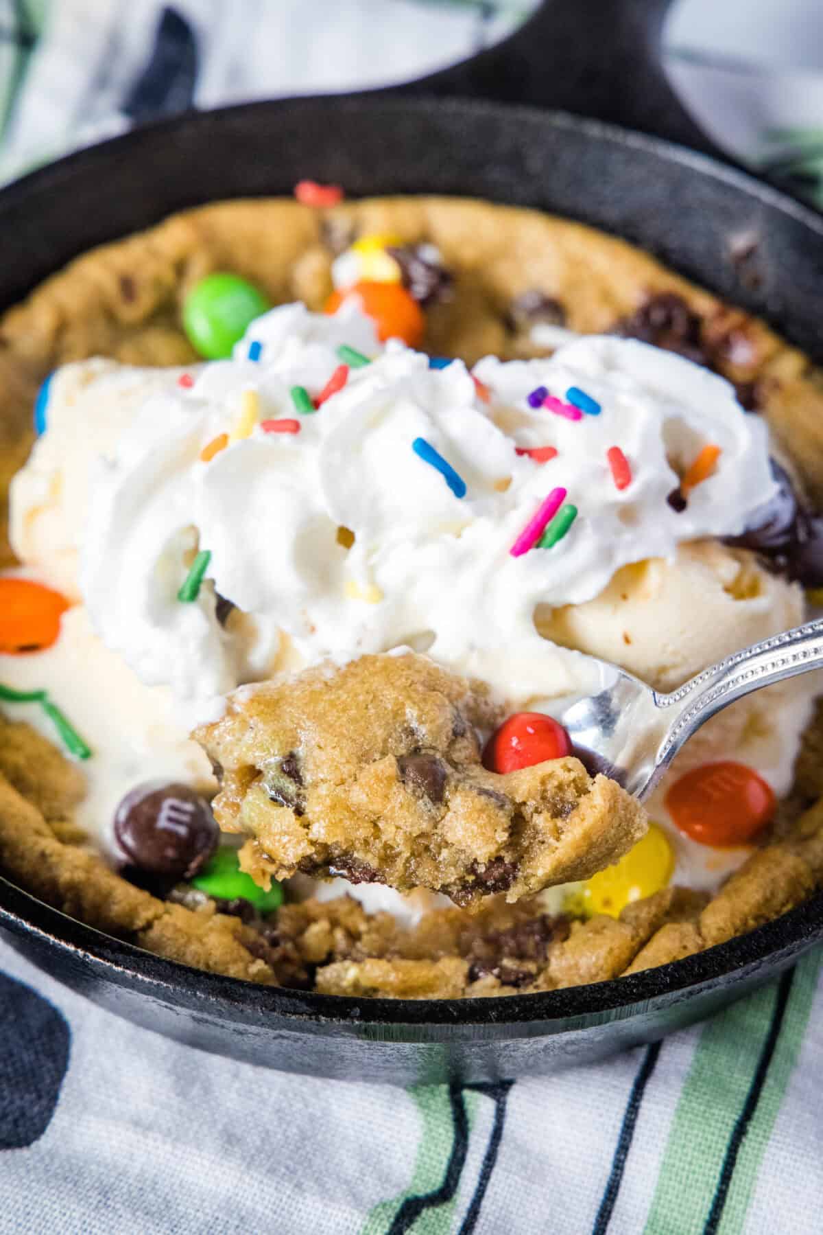 scooping out a bite of skillet cookie with whipped cream and toppings