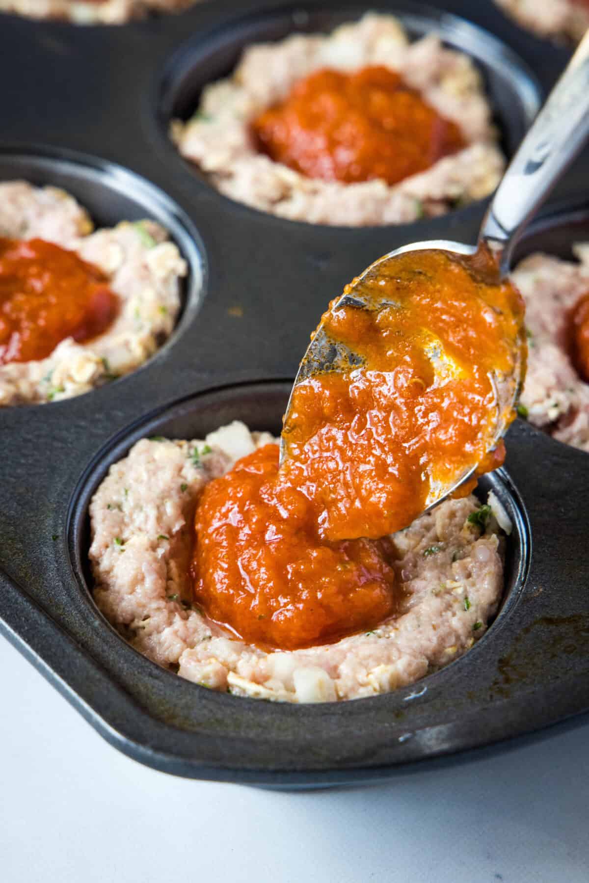 adding marinara sauce to turkey meatloaf cups
