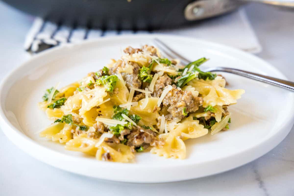 sausage kale pasta on a white plate