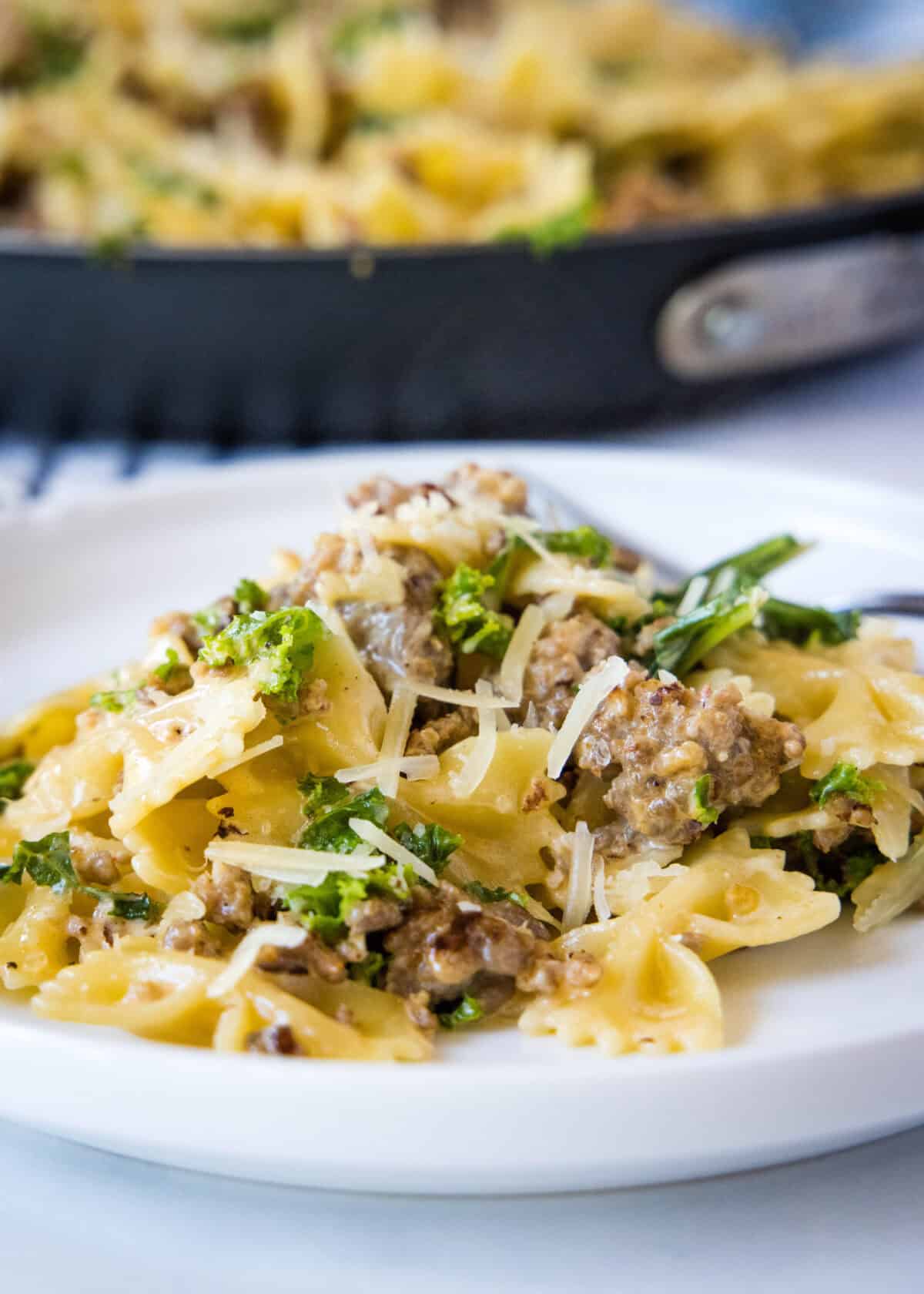 sausage kale pasta on a white plate