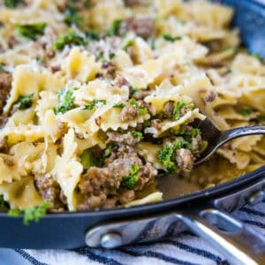 cropped close up scooping sausage kale pasta from the pan