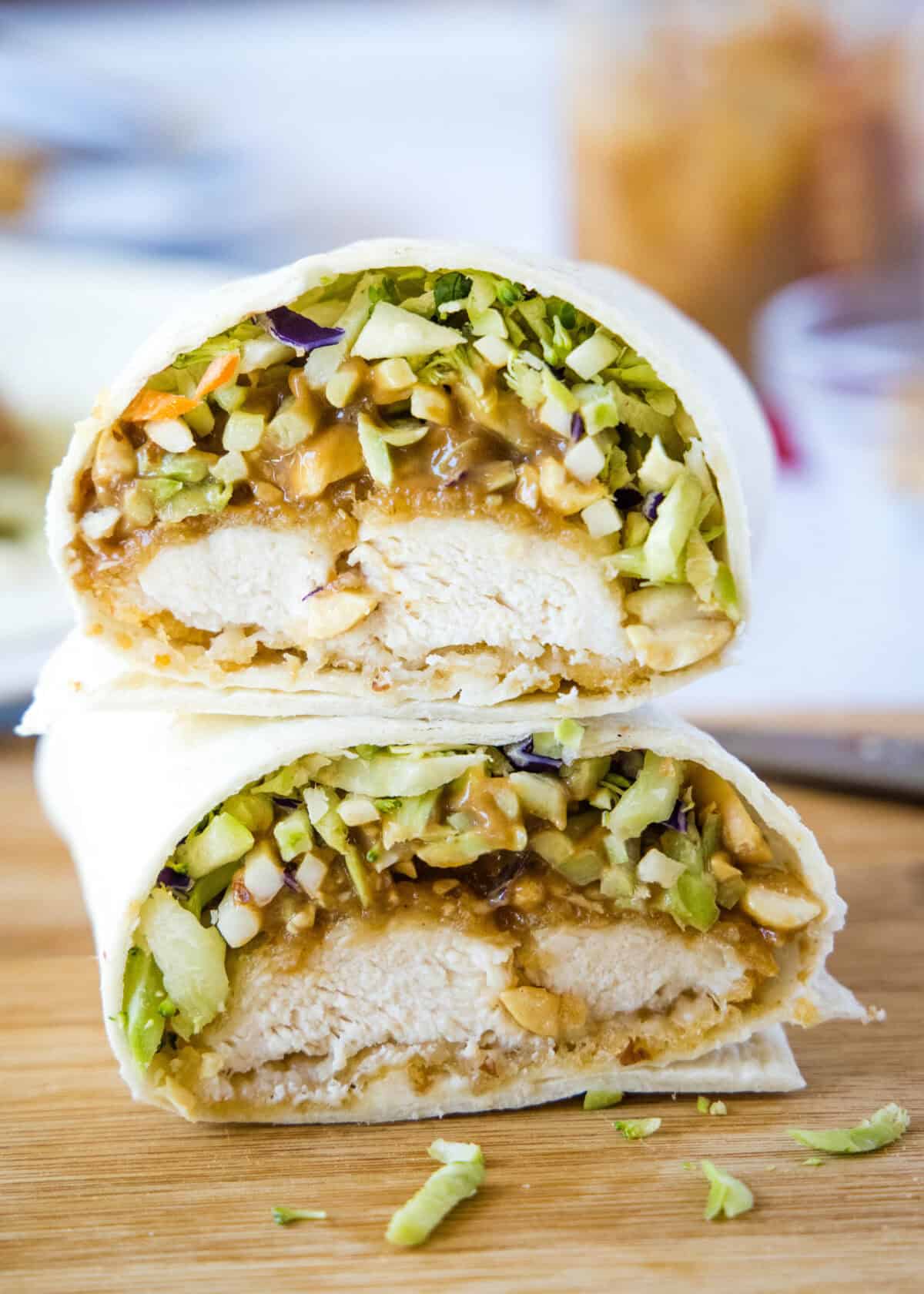 asian chicken wrap cut in half on cutting board