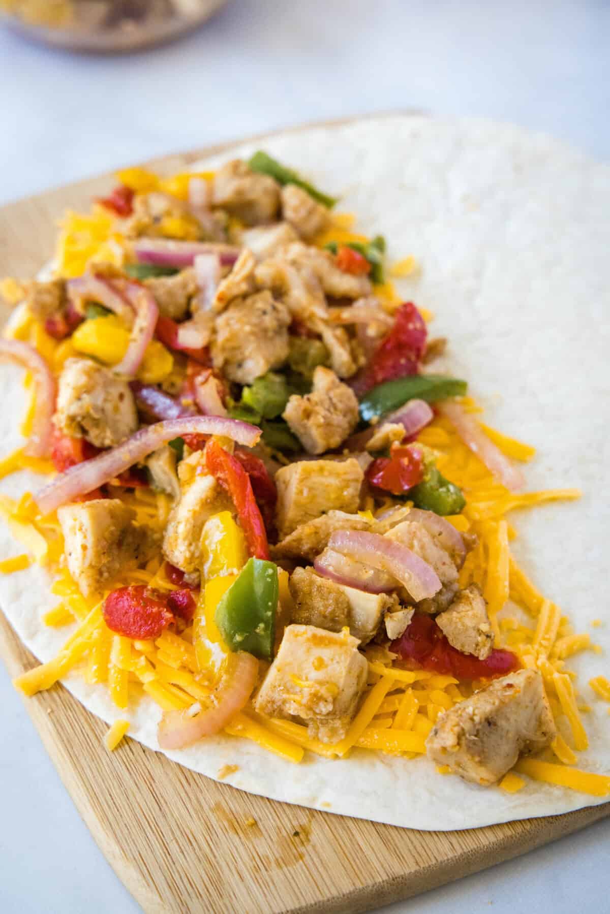adding chicken fajita quesadilla ingredients to a tortilla