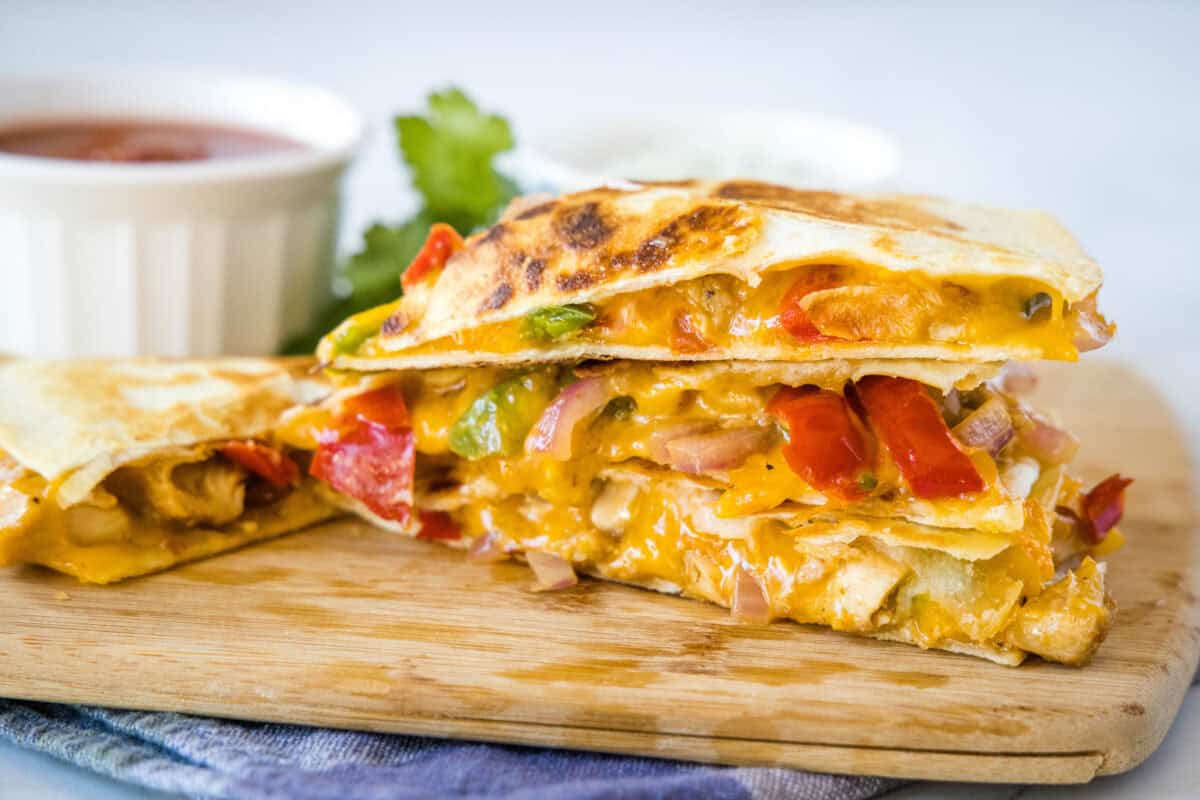 chicken fajita quesadilla slices stacked on a cutting board