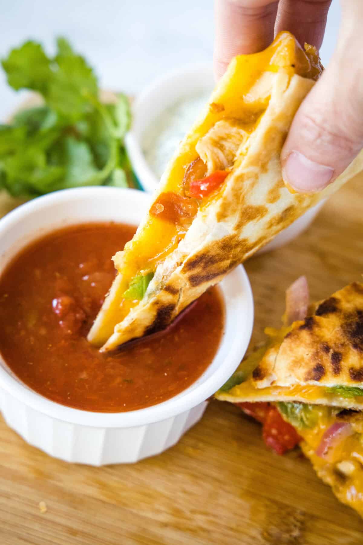 dipping chicken fajita quesadilla in salsa