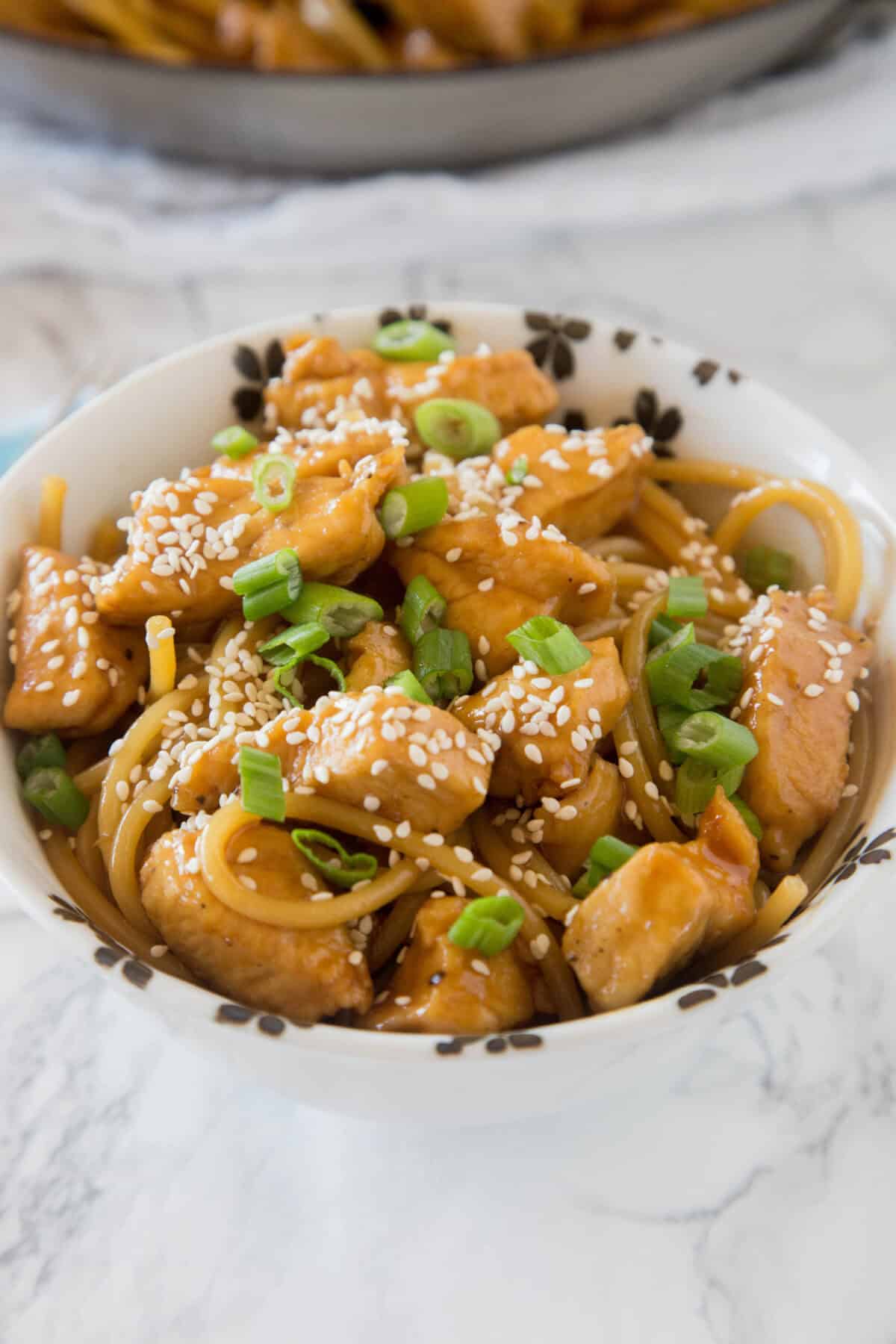 looking down on teriyaki chicken noodles in a white bowl