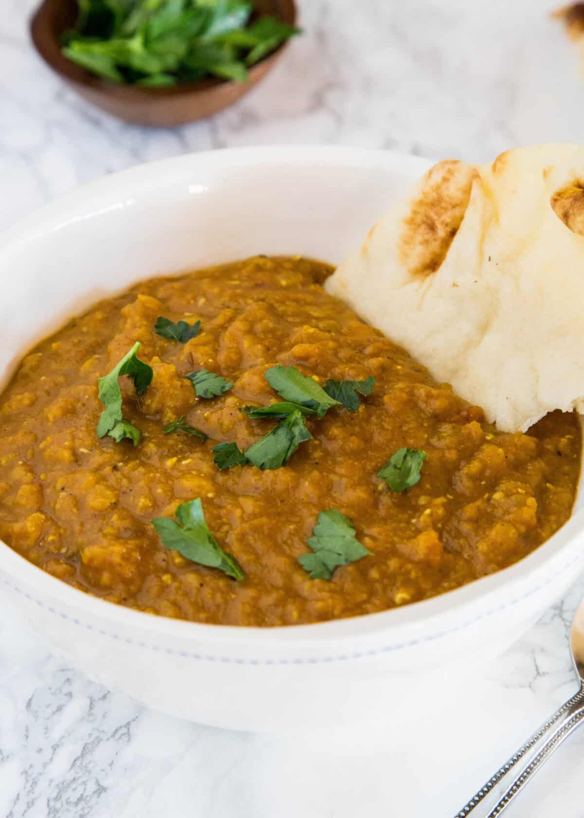indian lentil soup in a bowl with naan bread